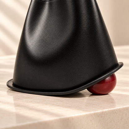 Détail de la base sculpturale et du pied sphérique bordeaux du Sac Signature Qavero noir